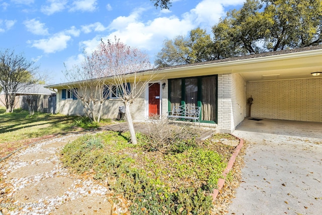 ranch-style house with an attached carport, brick siding, and driveway