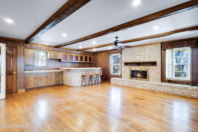 unfurnished living room with beam ceiling, plenty of natural light, a fireplace, and light wood finished floors