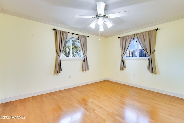 empty room with ceiling fan, wood finished floors, baseboards, and ornamental molding