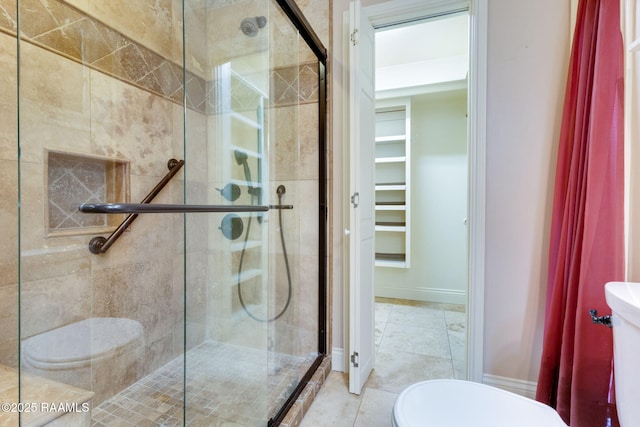 bathroom with tile patterned flooring, toilet, baseboards, and a stall shower