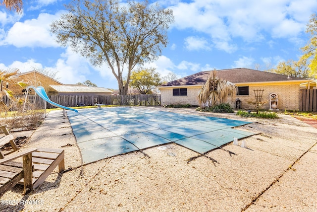 view of pool featuring a patio area, a fenced in pool, a water slide, and fence