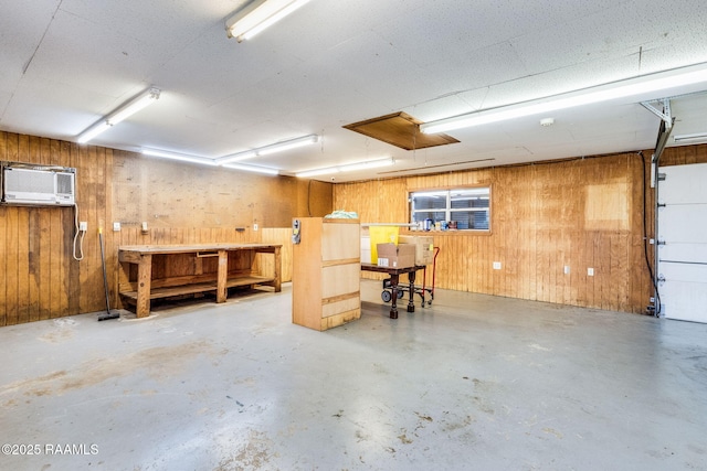 garage featuring a workshop area, wood walls, and a wall unit AC