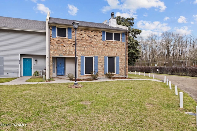 back of house with brick siding, a chimney, and a lawn