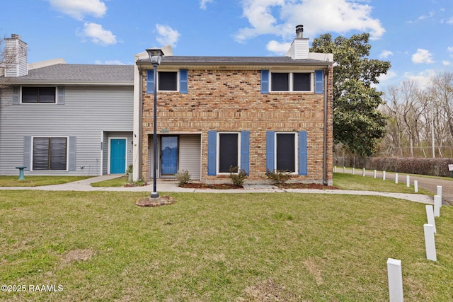 view of front of property featuring brick siding, a chimney, and a front lawn