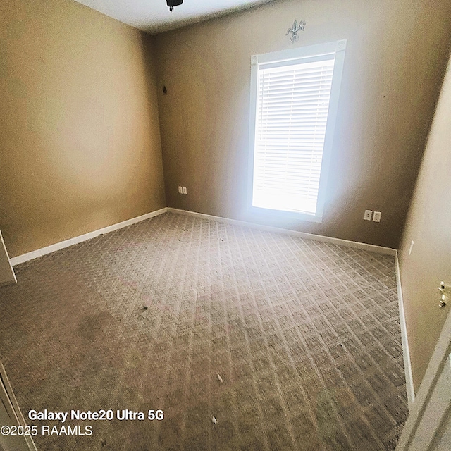 empty room featuring baseboards and carpet