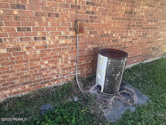 exterior details featuring cooling unit and brick siding