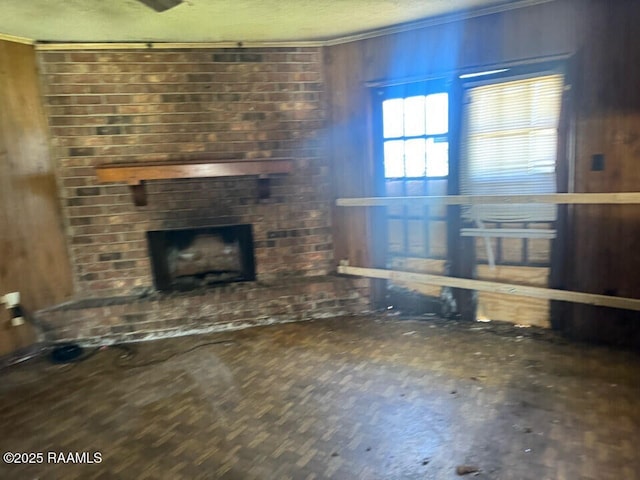 unfurnished living room with a brick fireplace, a textured ceiling, and ornamental molding