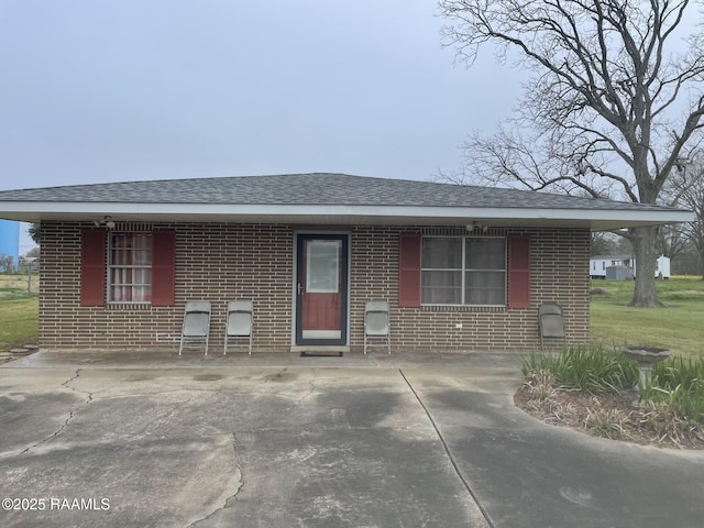 view of front facade with brick siding and a shingled roof