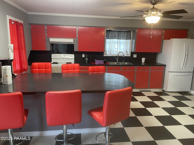 kitchen with under cabinet range hood, red cabinetry, light floors, white appliances, and a sink