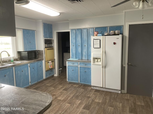 kitchen with wall oven, blue cabinetry, black microwave, white refrigerator with ice dispenser, and a sink