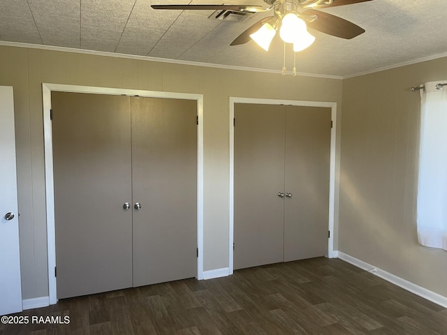 unfurnished bedroom with visible vents, two closets, crown molding, and wood finished floors