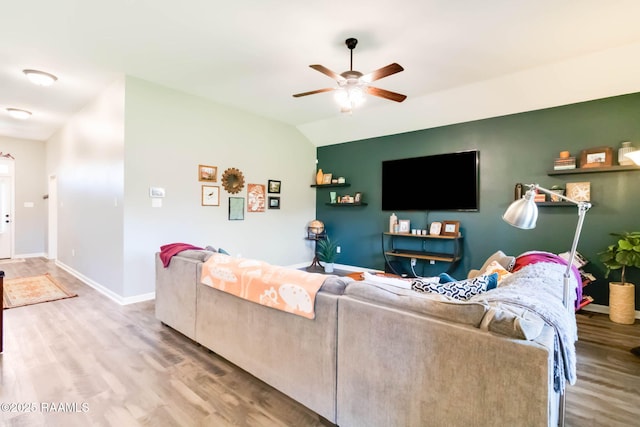 living area featuring baseboards, lofted ceiling, wood finished floors, and a ceiling fan