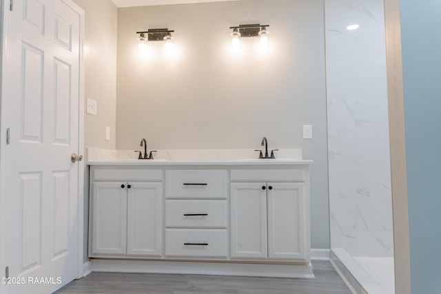 bathroom featuring a marble finish shower and a sink