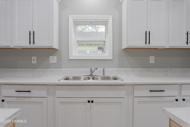 kitchen with a sink, white cabinets, and light countertops