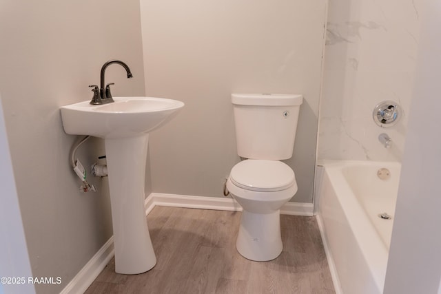 bathroom featuring toilet, wood finished floors, baseboards, and shower / bathtub combination