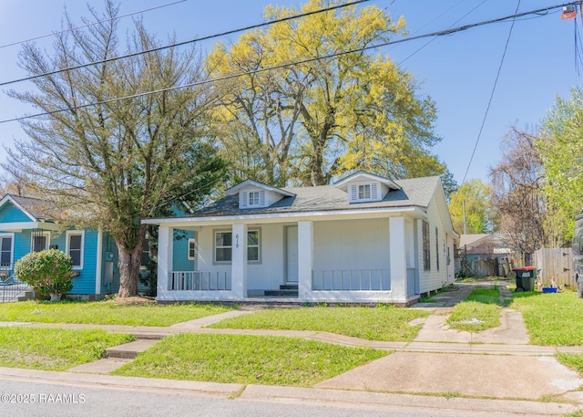 bungalow-style house featuring a front yard, a porch, fence, and a shingled roof