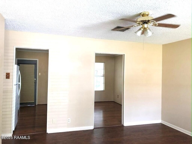 empty room with a textured ceiling, a ceiling fan, baseboards, and wood finished floors