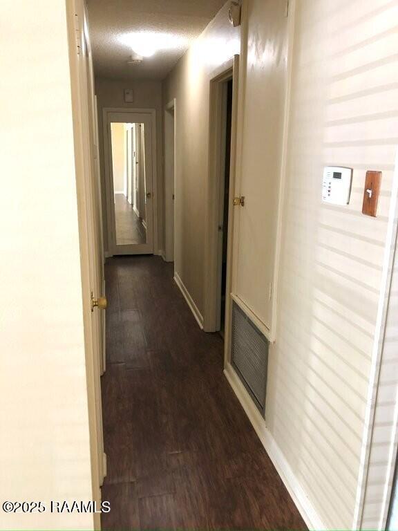 hall featuring dark wood finished floors, baseboards, and visible vents