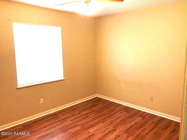 spare room featuring dark wood-style floors, ceiling fan, and baseboards