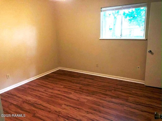 spare room featuring dark wood-type flooring and baseboards