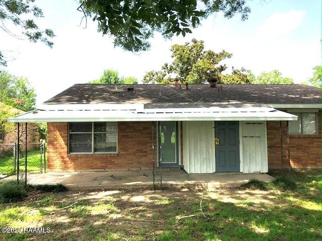 view of front of home featuring brick siding, a patio area, a shingled roof, and a gate