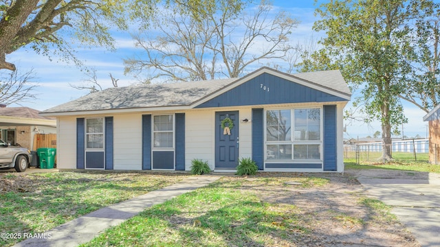 view of front of house featuring roof with shingles, a front yard, and fence