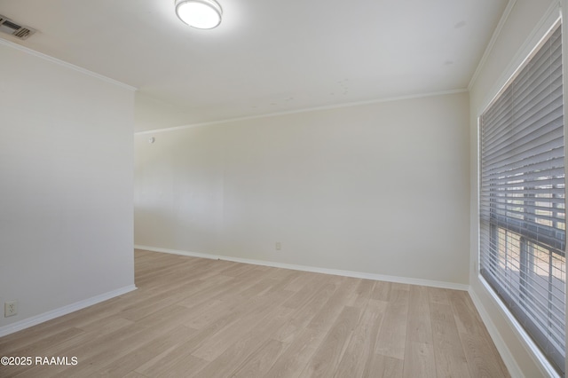 spare room with light wood-type flooring, baseboards, visible vents, and ornamental molding