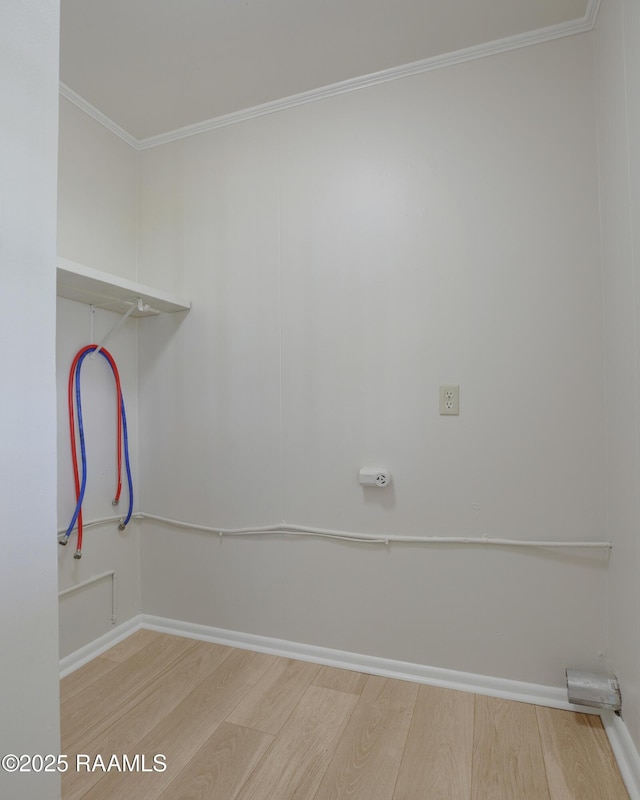 clothes washing area with ornamental molding, baseboards, and wood finished floors