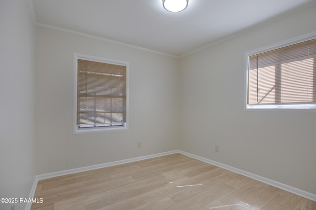 spare room with light wood-type flooring, baseboards, and ornamental molding