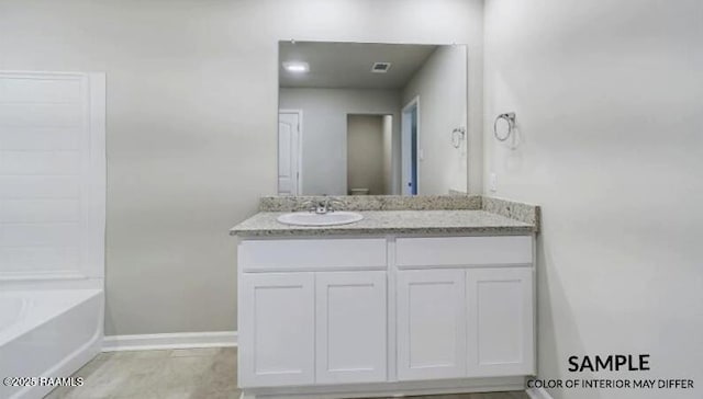 bathroom featuring vanity, visible vents, baseboards, and a bathing tub