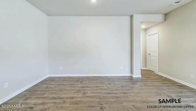 unfurnished room with wood finished floors, visible vents, and baseboards