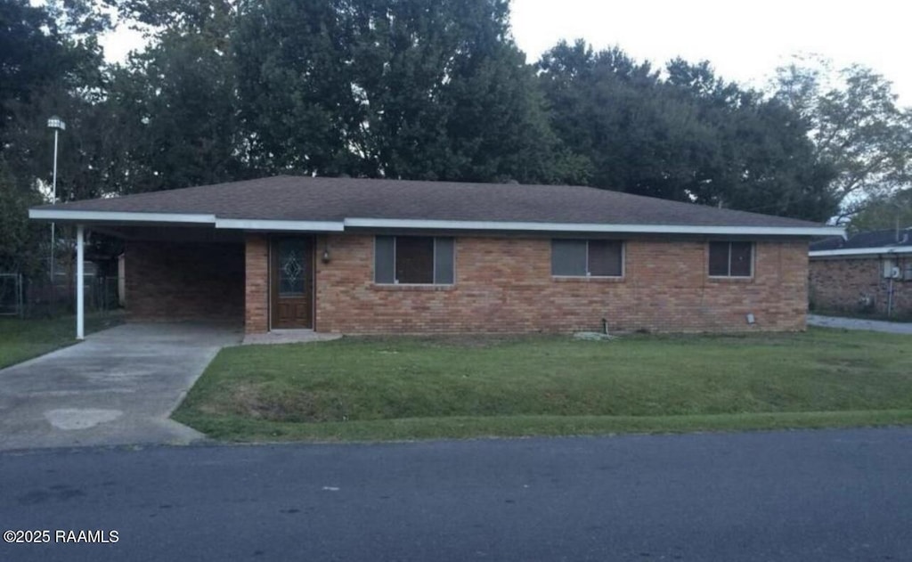 single story home featuring an attached carport, concrete driveway, brick siding, and a front yard