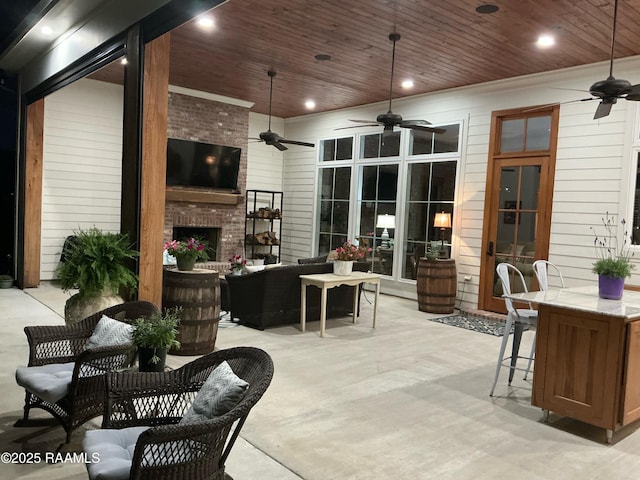 view of patio / terrace featuring ceiling fan and an outdoor living space with a fireplace