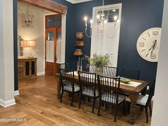 dining space featuring a chandelier, baseboards, and wood finished floors