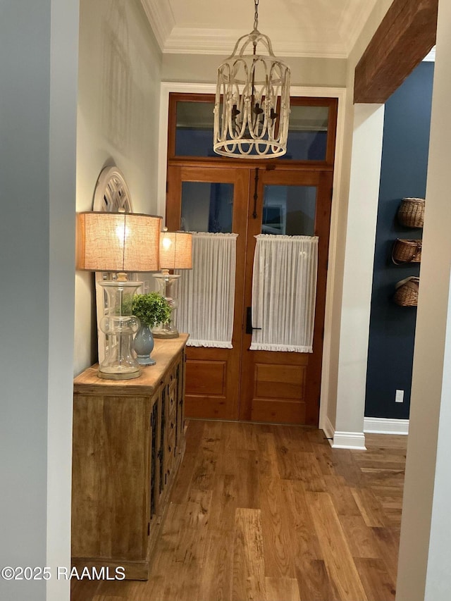 corridor with baseboards, a chandelier, ornamental molding, french doors, and wood finished floors