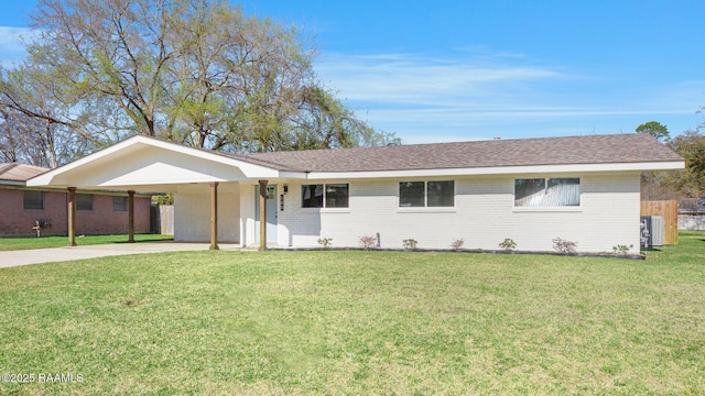 single story home featuring a front yard, driveway, a shingled roof, a carport, and brick siding