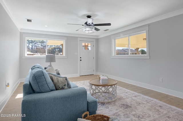 living room featuring visible vents, crown molding, ceiling fan, baseboards, and wood finished floors