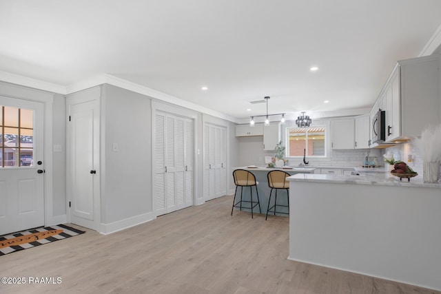 kitchen with light wood finished floors, stainless steel microwave, a breakfast bar, and light countertops