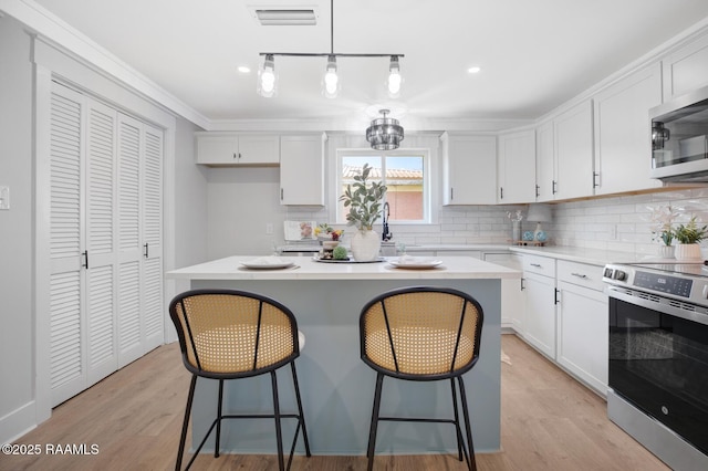 kitchen featuring stainless steel appliances, a kitchen bar, visible vents, and white cabinetry