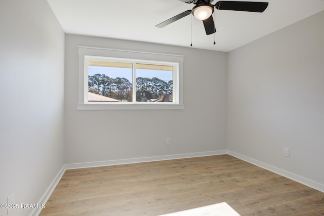 spare room featuring light wood finished floors, ceiling fan, and baseboards