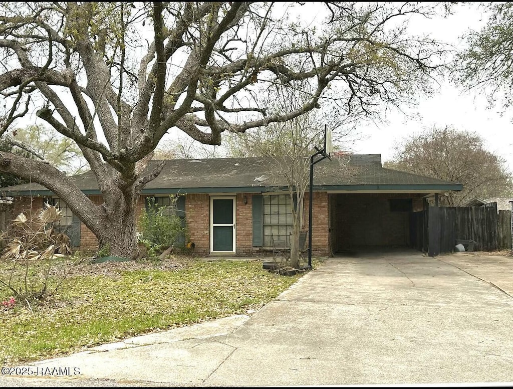 single story home featuring concrete driveway, fence, a carport, and brick siding