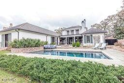 rear view of property featuring an outdoor pool and a chimney