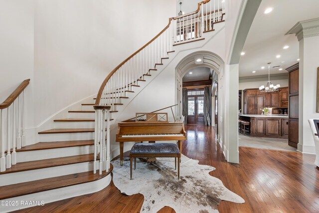 306 Princeton Woods Loop, Lafayette, LA 70508 - entrance foyer with a notable chandelier, dark wood-style floors, arched walkways, a towering ceiling, and stairs
