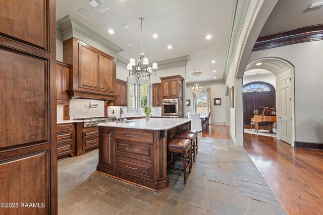306 Princeton Woods Loop, Lafayette, LA 70508 - kitchen featuring light countertops, stainless steel gas stovetop, an island with sink, and visible vents