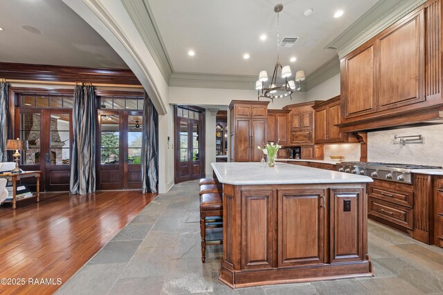 306 Princeton Woods Loop, Lafayette, LA 70508 - kitchen with visible vents, a center island, light countertops, an inviting chandelier, and stainless steel gas stovetop