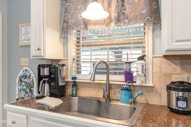 kitchen featuring a sink, dark countertops, and white cabinets