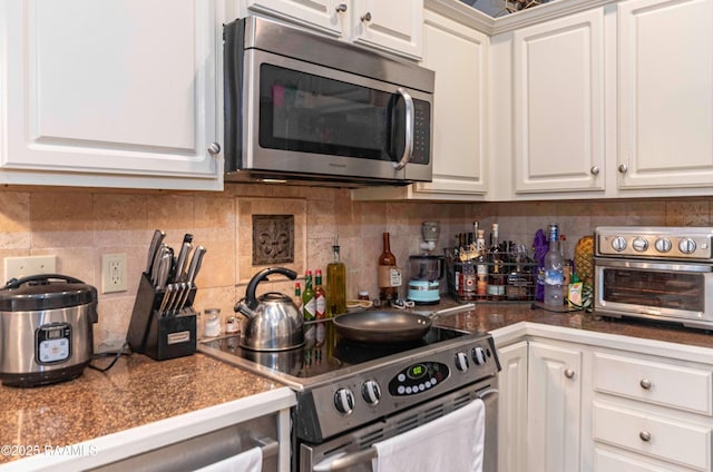 kitchen featuring backsplash, a toaster, white cabinets, and stainless steel appliances