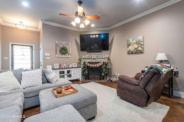 living area featuring visible vents, a ceiling fan, a fireplace, crown molding, and baseboards