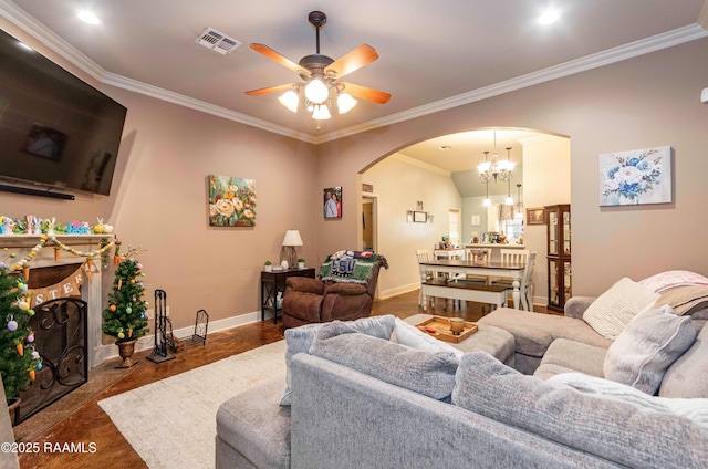 living area with visible vents, baseboards, ornamental molding, a fireplace, and arched walkways