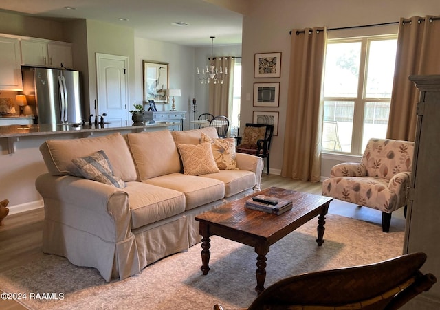 living area featuring a chandelier, baseboards, and light wood-style floors